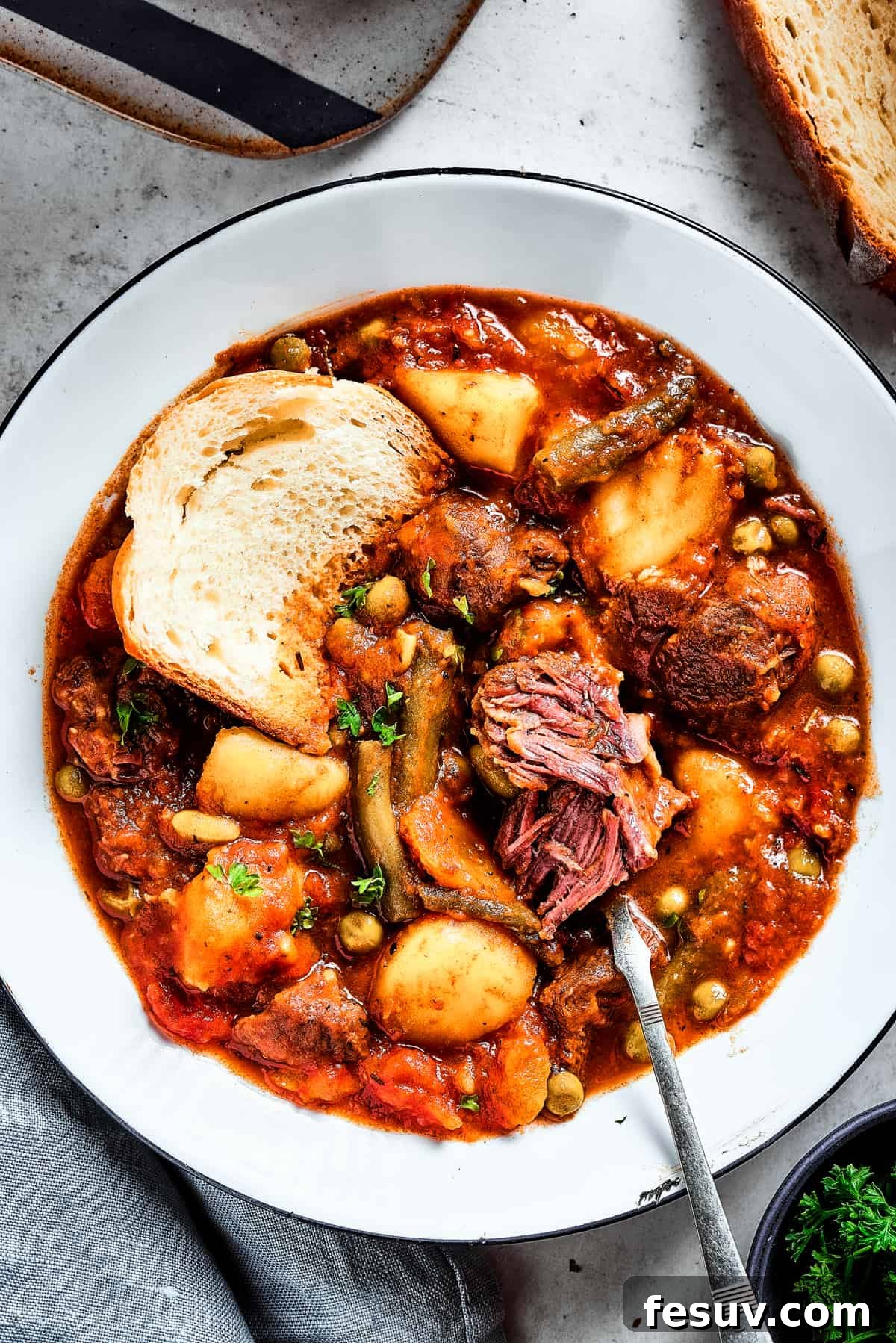 As the air gets crisper and the leaves turn golden, it's time to cozy up with a bowl of pure comfort - this old-fashioned Mulligan Stew! A bowl of stew with a spoon. A chunk of beef has been pulled apart to show the texture.