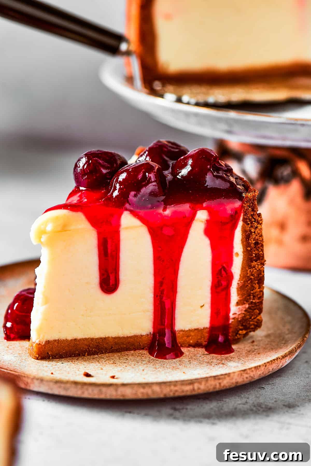 A delectable slice of cherry cheesecake, topped with fresh cherries and mint, served on a small elegant dessert plate.