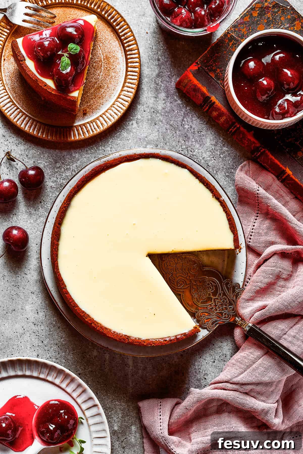 An overhead shot of a freshly baked cherry cheesecake with a slice neatly removed, revealing its creamy layers and crust.