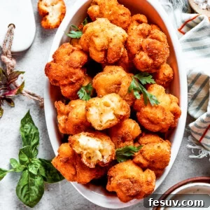Overhead view of a serving bowl full of mac and cheese bites, next to more of them and garnished with fresh herbs.