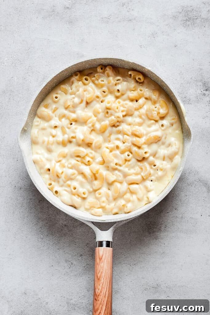 A large saucepan filled to the brim with creamy, golden macaroni and cheese, ready for the next step.