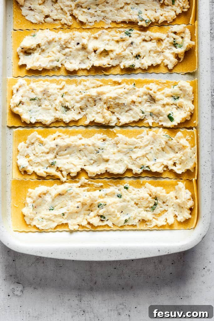 Easy lasagna roll ups have a beefy and herbaceous tomato sauce, a creamy cheese filling, tender pasta, and tons of melted cheese. Overhead view of lasagna noodles with a cheese mixture spread over them.