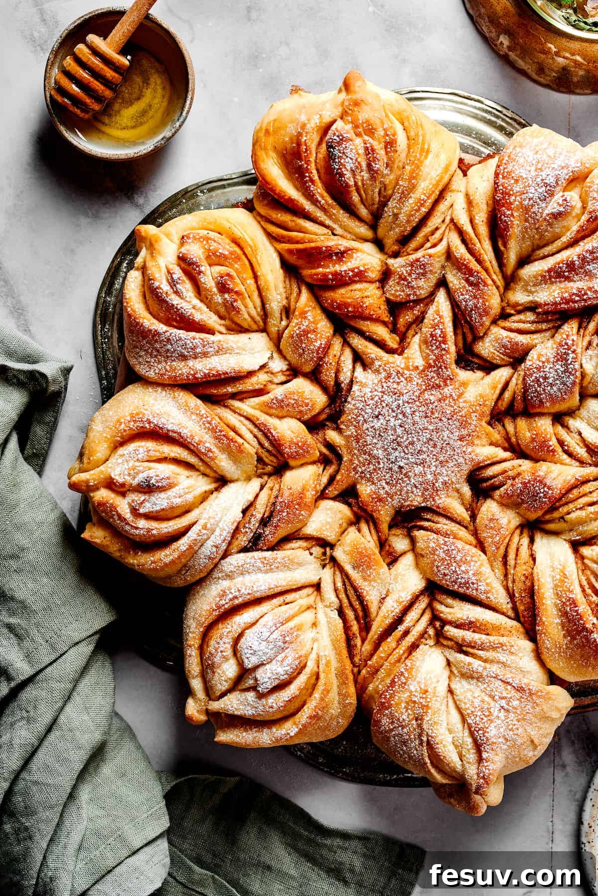 An overhead view of a beautifully baked pull-apart Star Bread, generously dusted with powdered sugar and ready to serve. This festive holiday dessert showcases its intricate twisted design and golden-brown crust.