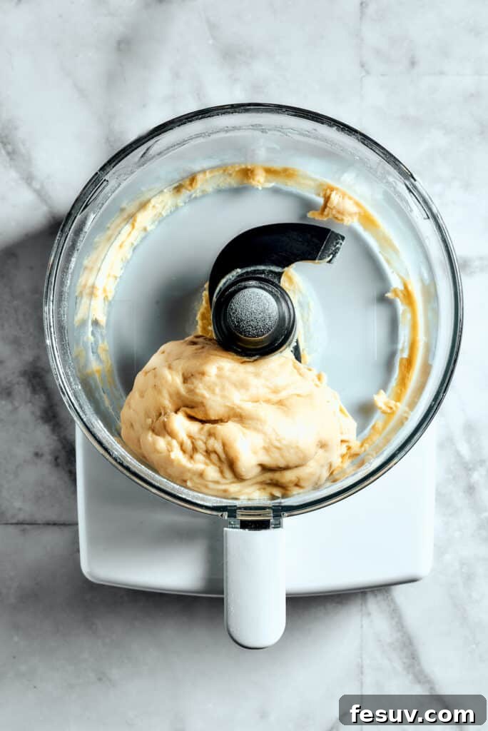 Overhead view of the star bread dough forming into a cohesive ball within a food processor, signaling it's almost ready for kneading.