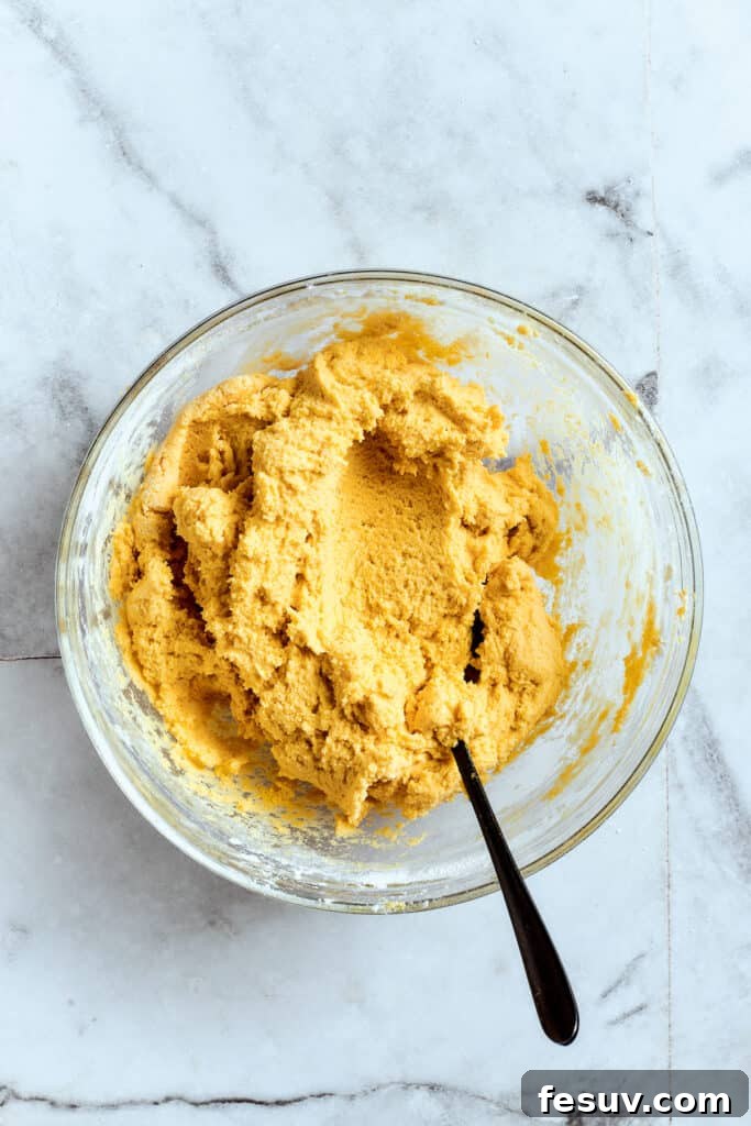 Overhead view of a mixing bowl filled with lemon cookie dough and a spoon.