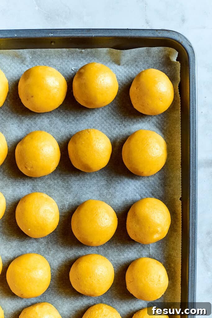 Overhead view of lemon cookie dough balls on a baking sheet.