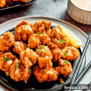 A plate of bang bang chicken with a lemon slice and a pair of chopsticks, next to a napkin and another lemon slice.