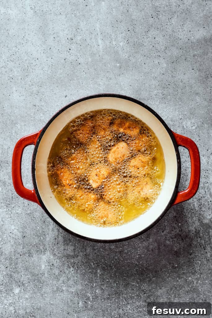 Overhead view of chicken frying in a dutch oven.