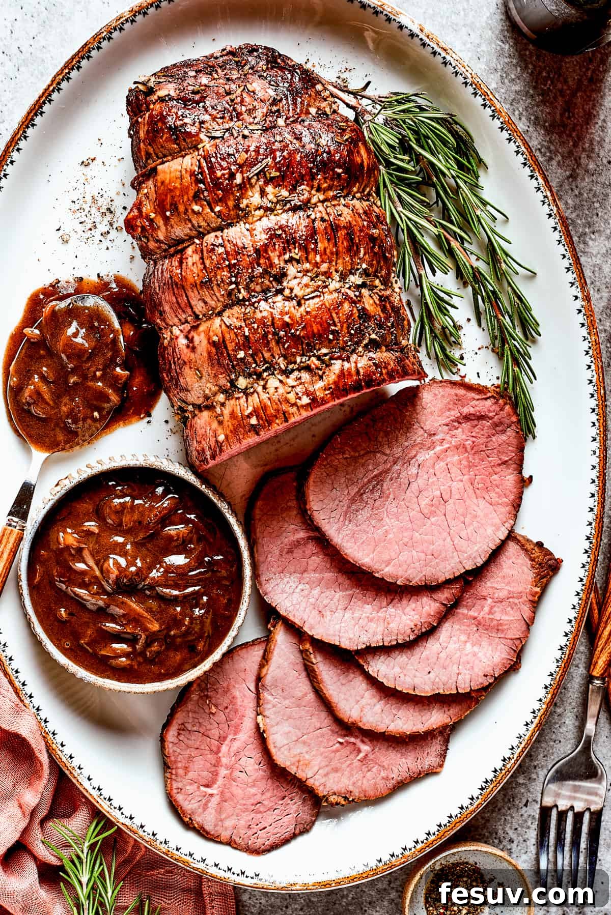 Juicy Top Round Roast with Caramelized Onion Gravy - Perfect for Holidays Top view of a perfectly sliced beef roast with rich brown gravy drizzled over it, garnished with fresh herbs, ready to be served for a special meal.
