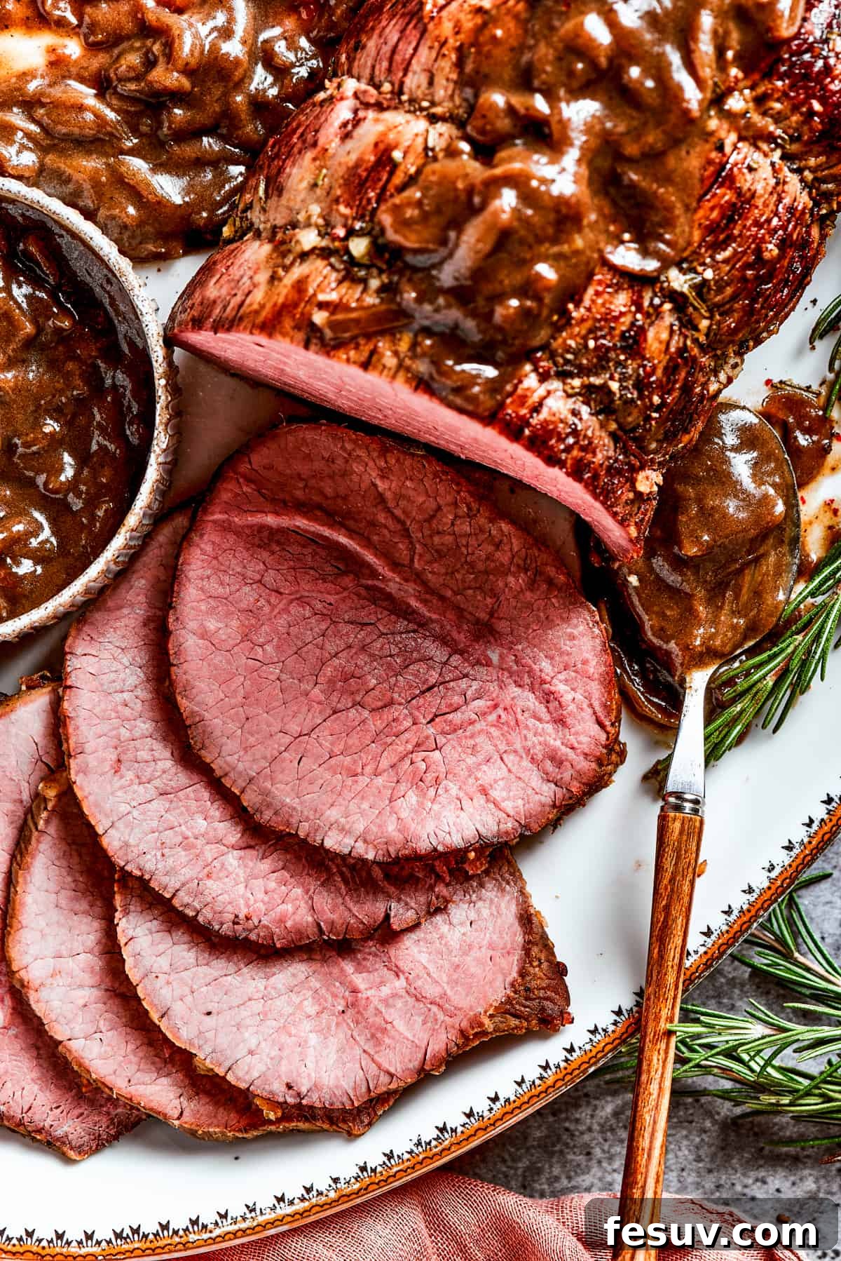 Tender, Sliced Top Round Roast Close-up view of thinly sliced, perfectly cooked top round roast, showcasing its tender, juicy texture and herb crust.