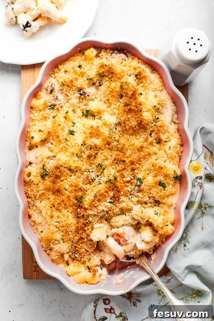 A freshly baked pan of seafood mac and cheese, bubbly and golden, with a serving spoon poised to scoop a portion.