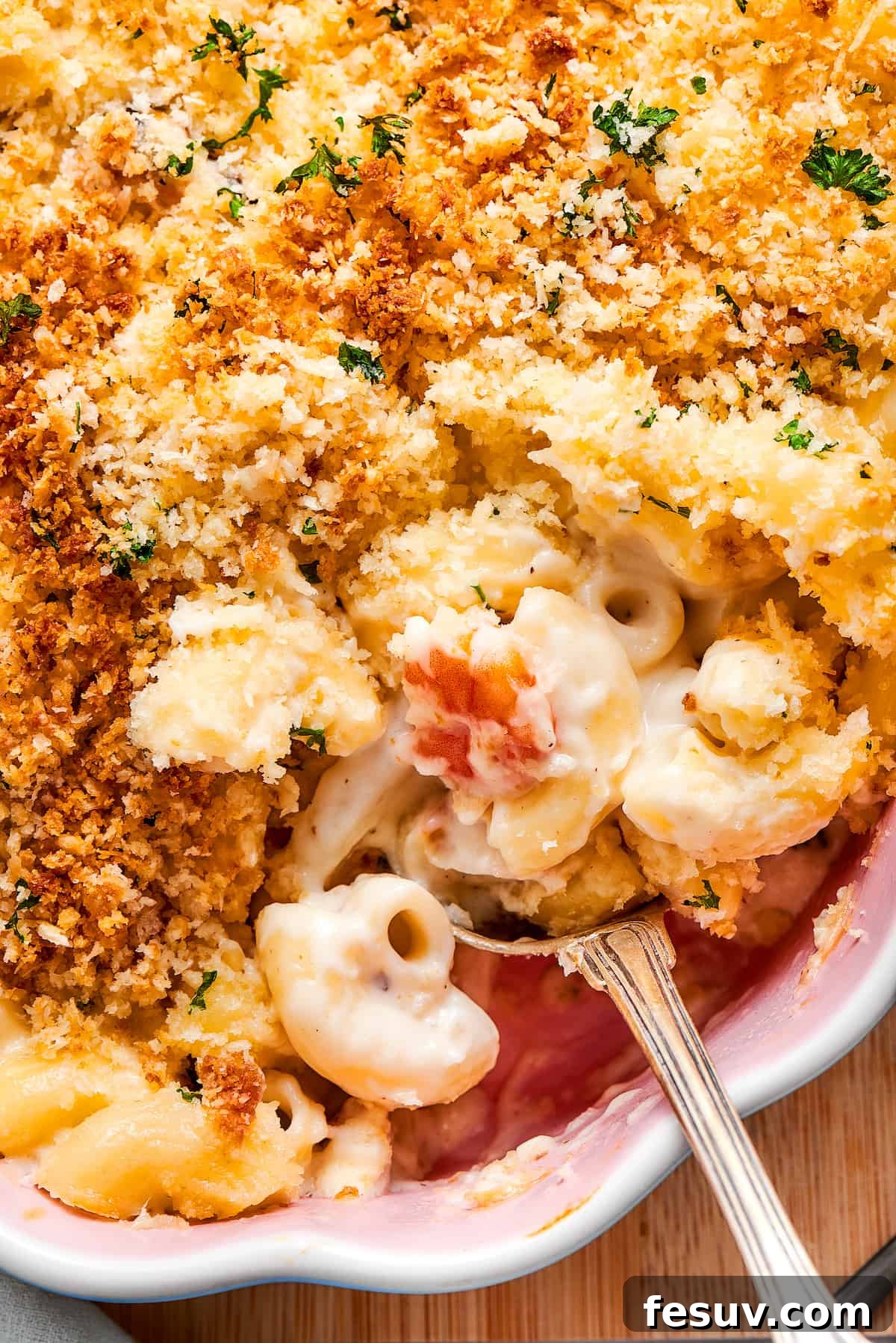 A close-up of a spoonful of creamy seafood mac and cheese, showing pieces of seafood and rich sauce.