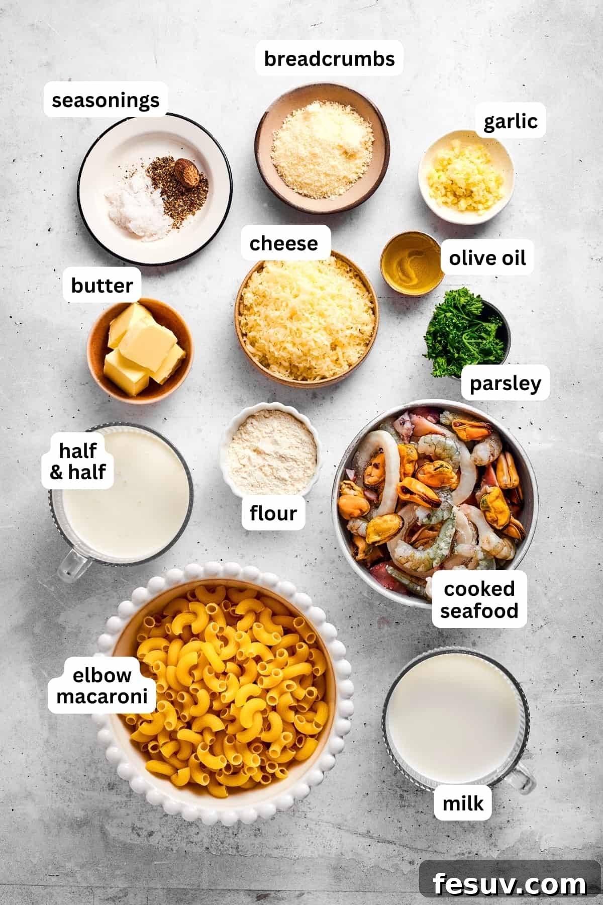 An overhead view of all the fresh ingredients laid out for making seafood mac and cheese, including pasta, cheese, milk, and various seafood.