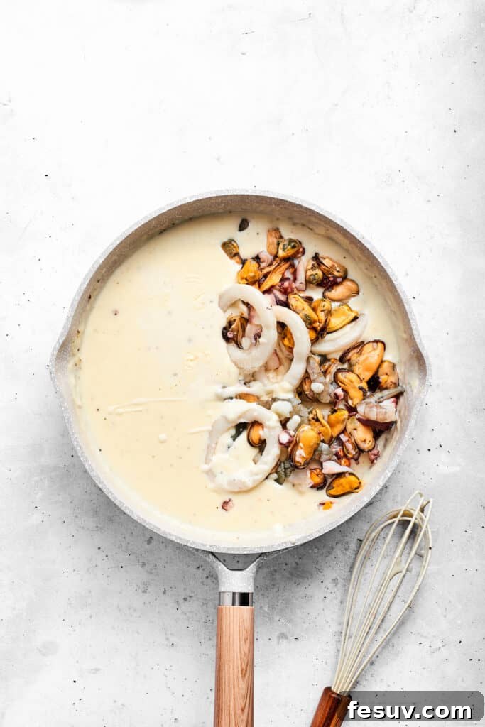 Gently adding cooked seafood, like shrimp and crab, into the creamy cheese sauce.