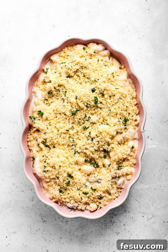 Seafood mac and cheese casserole, generously topped with parmesan breadcrumbs, ready for the oven.