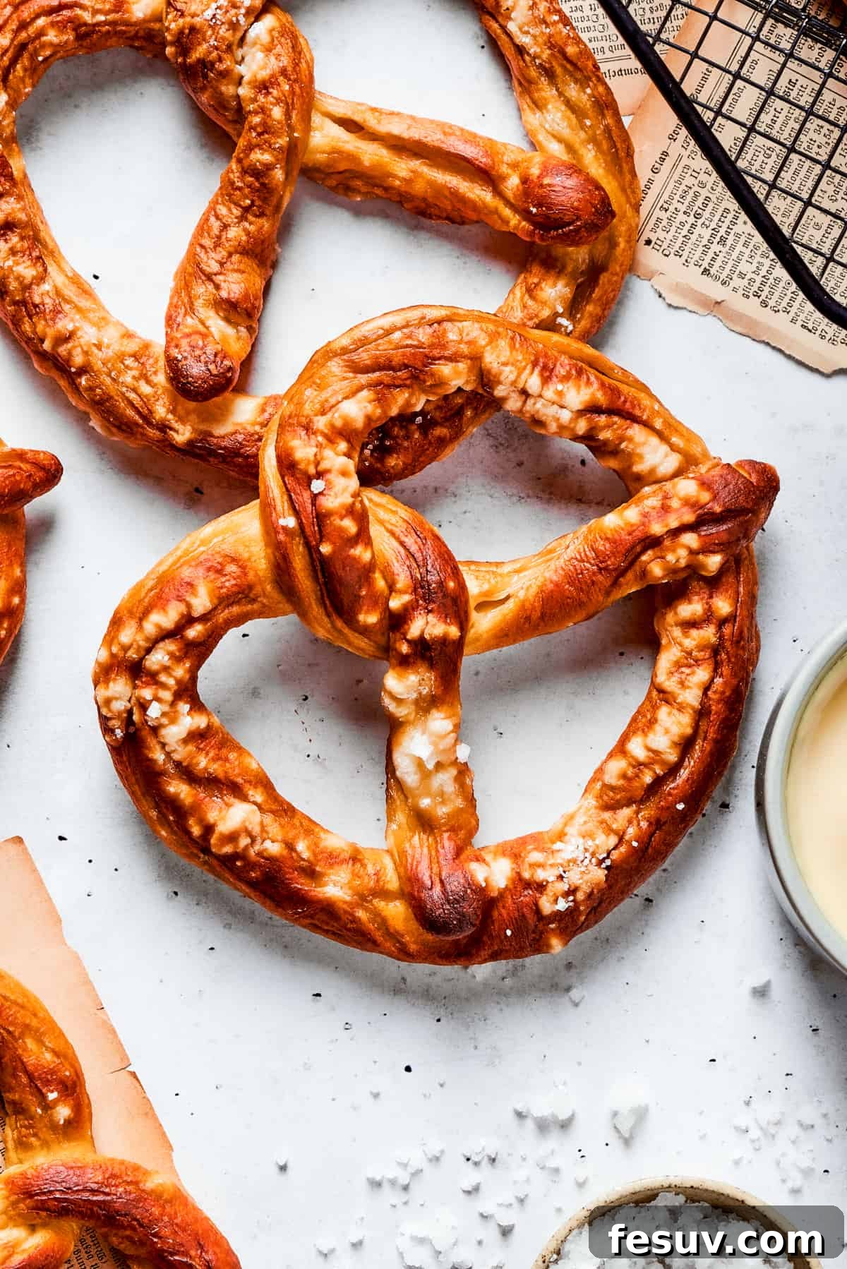 A top-down shot of several baked soft pretzels, golden brown and sprinkled with coarse salt, ready to be enjoyed.