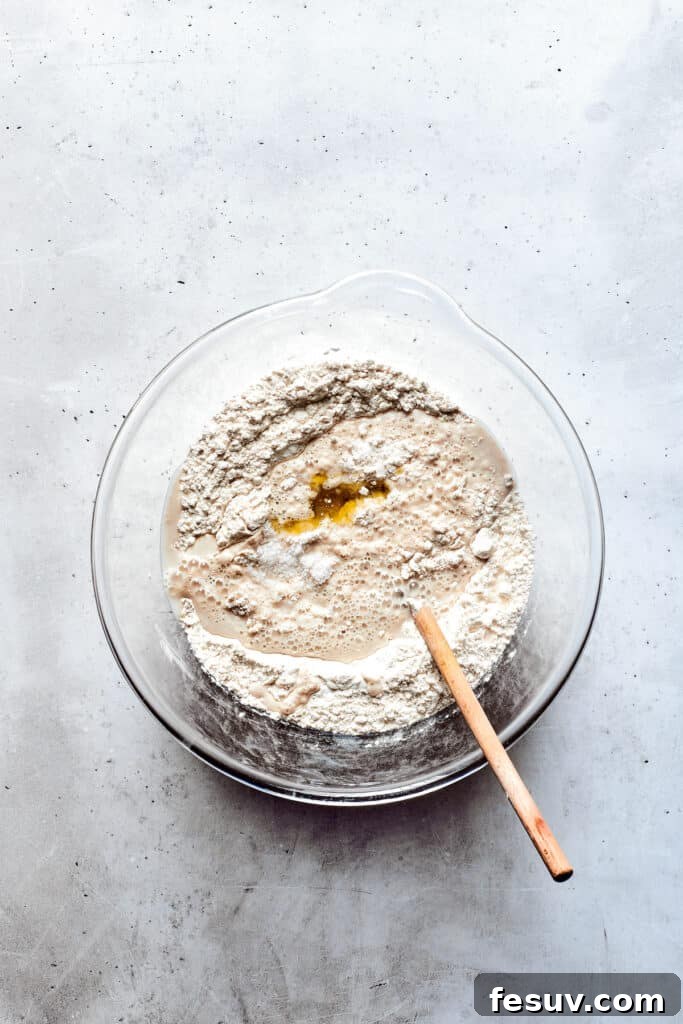 A glass bowl of soft pretzel dough after its first rise, looking perfectly proofed and airy.