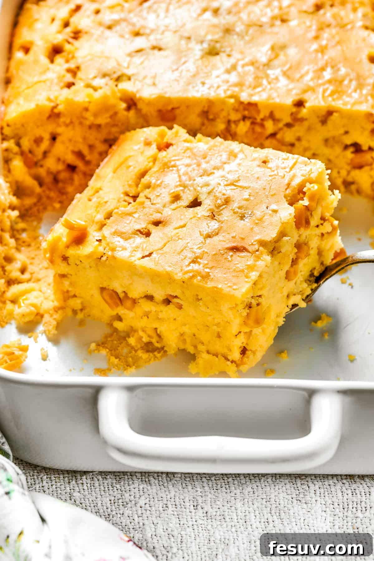 Golden Cloud Corn Souffle 4 A perfectly baked square of corn souffle nestled in a white baking dish.