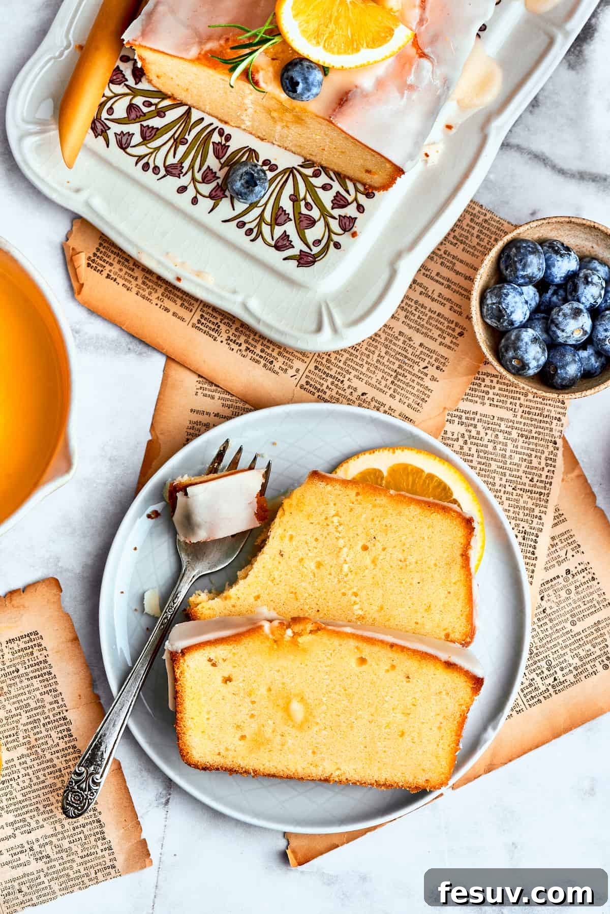 Slices of orange cake are arranged on a blue plate while a fork cuts into one of the pieces.