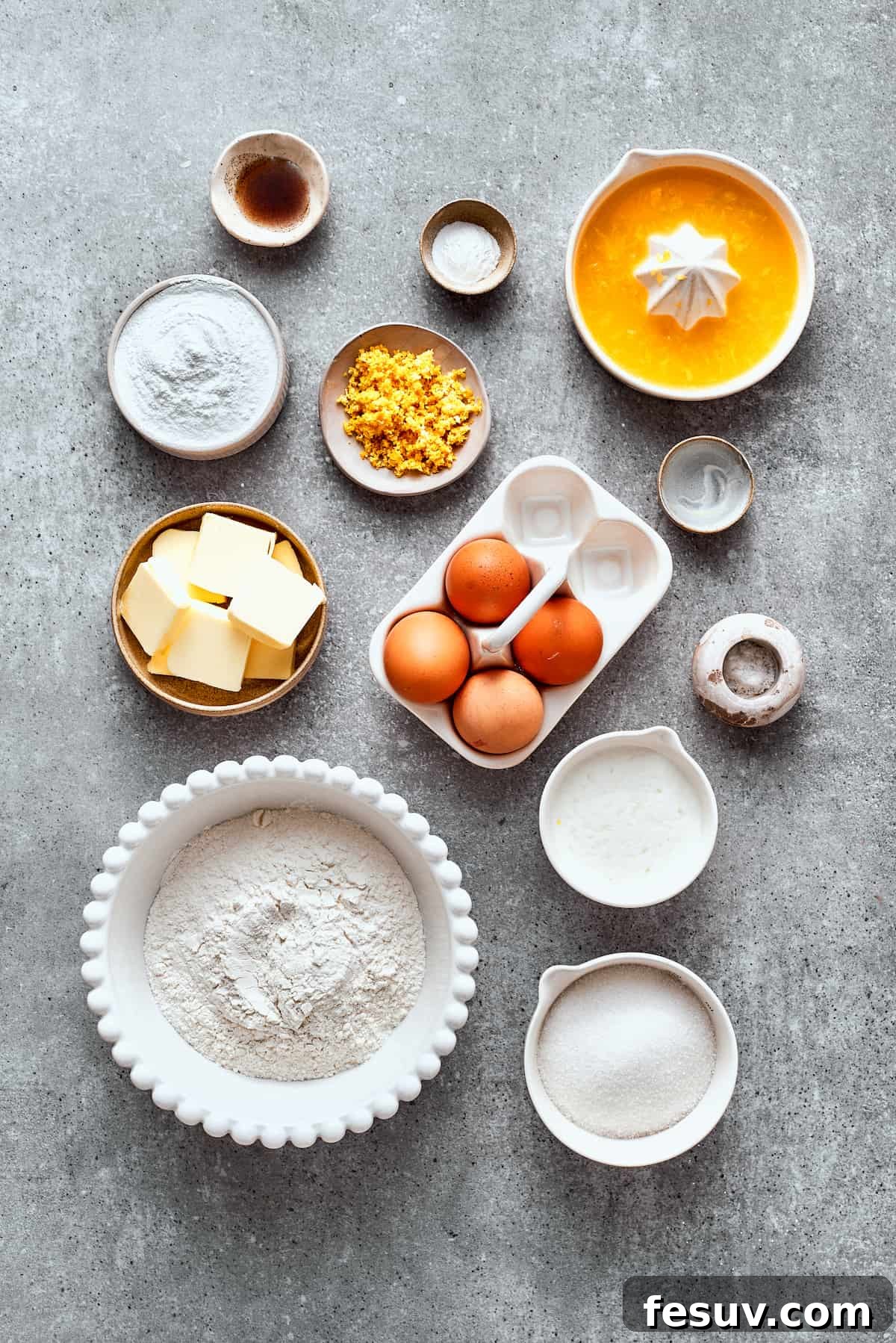The ingredients needed for orange cake are shown portioned out: eggs, flour, sugar, orange juice, orange zest, orange liqueur, butter, buttermilk, baking powder, salt.
