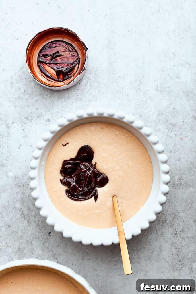 Melted chocolate is carefully stirred into a portion of the cheesecake filling in a bowl, creating a rich chocolate cheesecake layer for the Turtle Cheesecake.