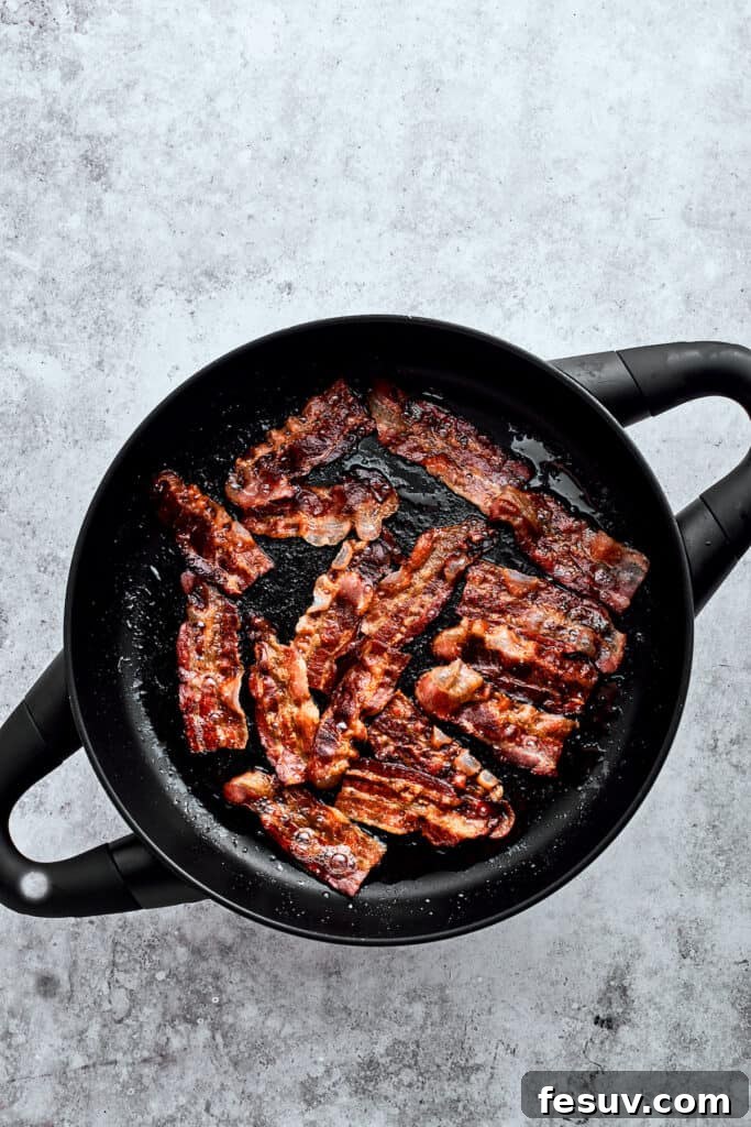 Browning bacon slices in a cast iron pot.