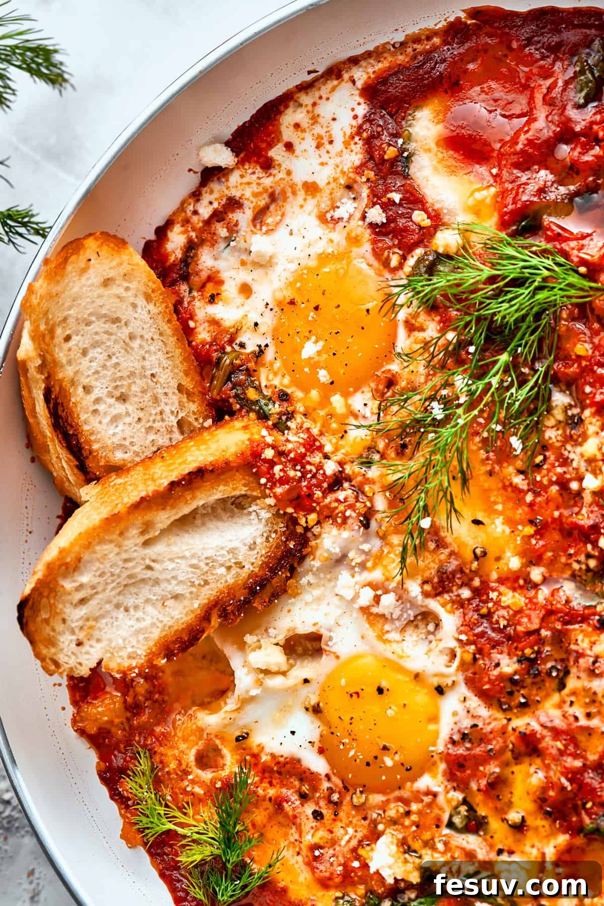 Toasted Bread Soaking Up the Delicious Eggs in Purgatory Sauce A close-up image showing two slices of golden, toasted bread nestled directly into the rich, red sauce of cooked Eggs in Purgatory, ready for dipping.