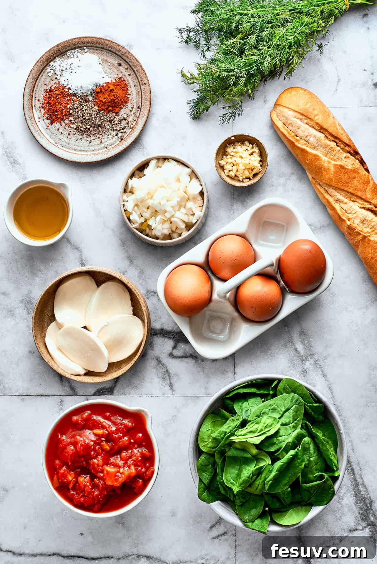 Fresh Ingredients for Spicy Eggs in Purgatory The fresh ingredients for Eggs in Purgatory are neatly arranged on a white background: eggs, bread, fresh mozzarella cheese, vibrant spinach, diced tomatoes, aromatic garlic, olive oil, a selection of spices, and fresh dill.