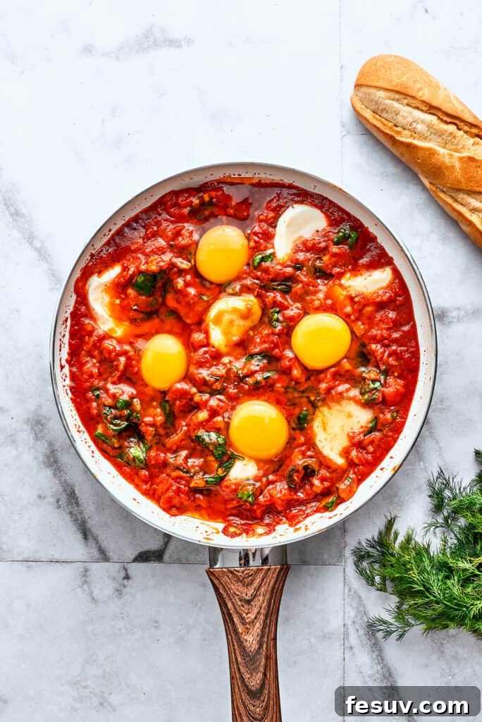 Cooked Eggs in Purgatory with Mozzarella and Runny Yolks A skillet of perfectly cooked Eggs in Purgatory showcases bright white mozzarella slices and vibrant yellow egg yolks nestled in a rich red tomato sauce, creating an inviting visual.