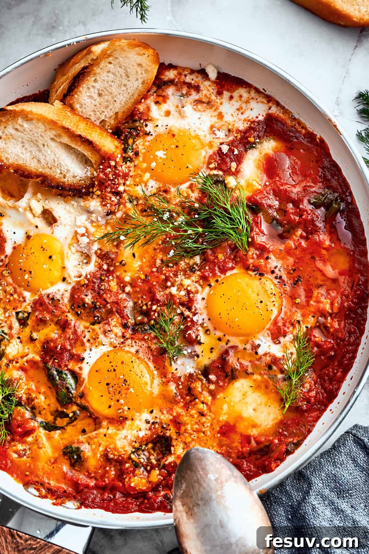 Close-Up of Finished Eggs in Purgatory with Garnish and Toasted Bread An overhead close-up shot of a skillet filled with cooked Eggs in Purgatory, beautifully garnished with fresh parsley and surrounded by slices of toasted bread.