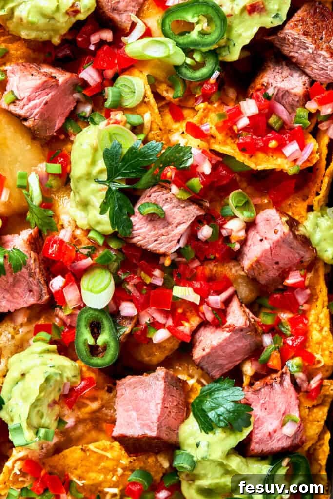 Chunks of juicy steak and peppers top a pan of steak nachos.