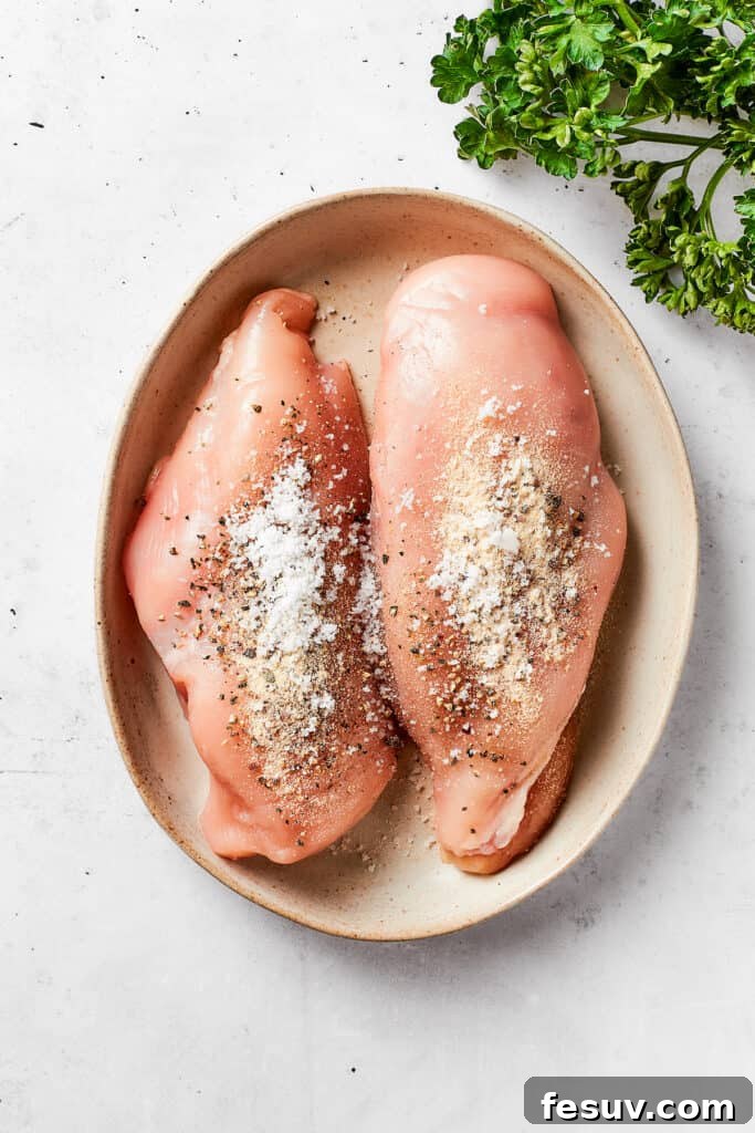Two seasoned chicken breasts rest in an oval serving dish.