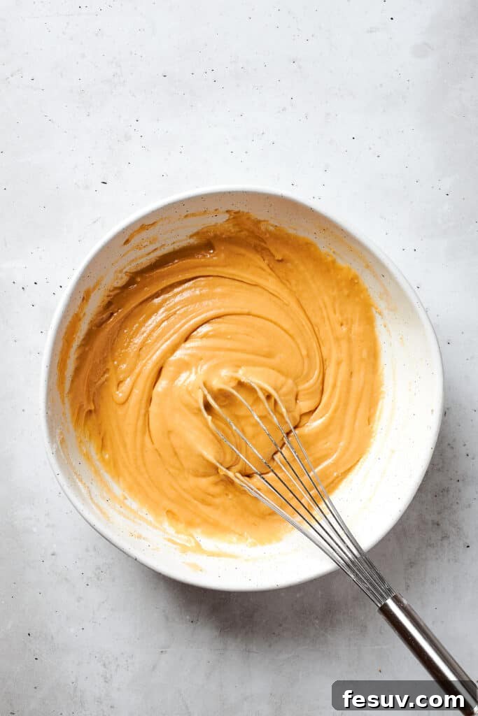 Blonde Brownies | Vanilla Blondies with White Chocolate and Pecans! A whisk is used to gently incorporate all the dry ingredients into the wet batter, forming a smooth blonde brownies mixture without overmixing.