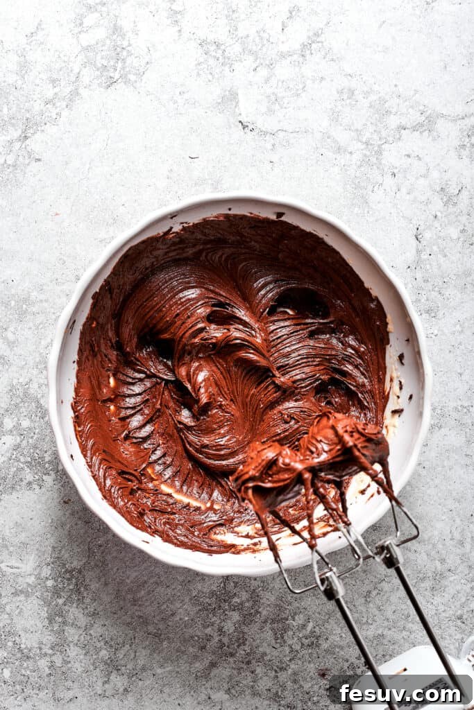 The dark, glossy chocolate and egg mixture being further beaten to achieve a smooth consistency.