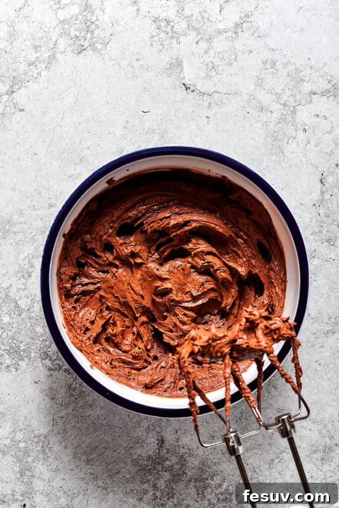 The chocolate-egg mixture being gradually beaten into the whipped butter, combining to form the rich pie filling.
