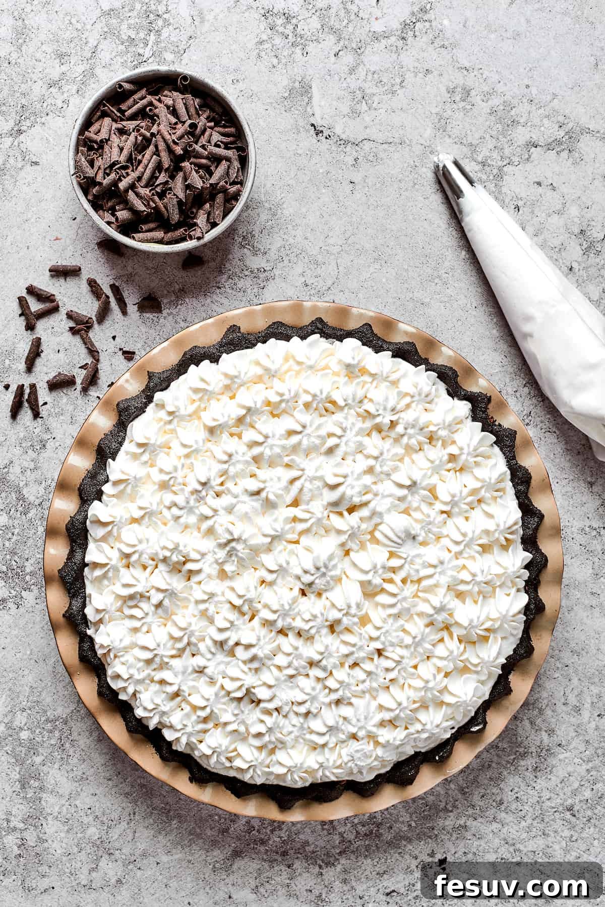 Delicious swirls of homemade whipped cream being piped artistically on top of the rich French Silk Pie filling.