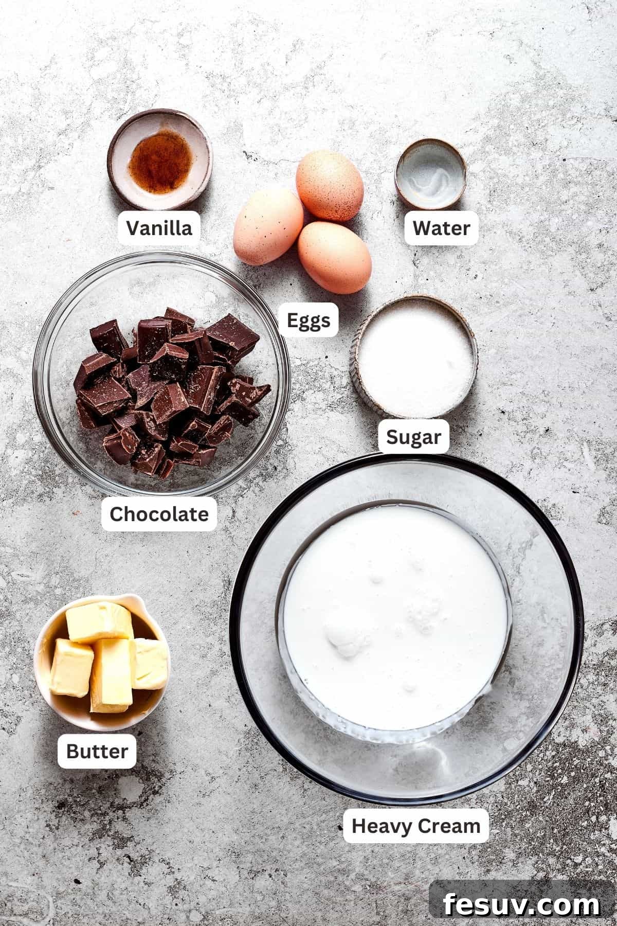 All the filling ingredients for French Silk Pie neatly arranged: chopped chocolate, fresh eggs, vanilla extract, heavy cream, water, granulated sugar, and softened butter.