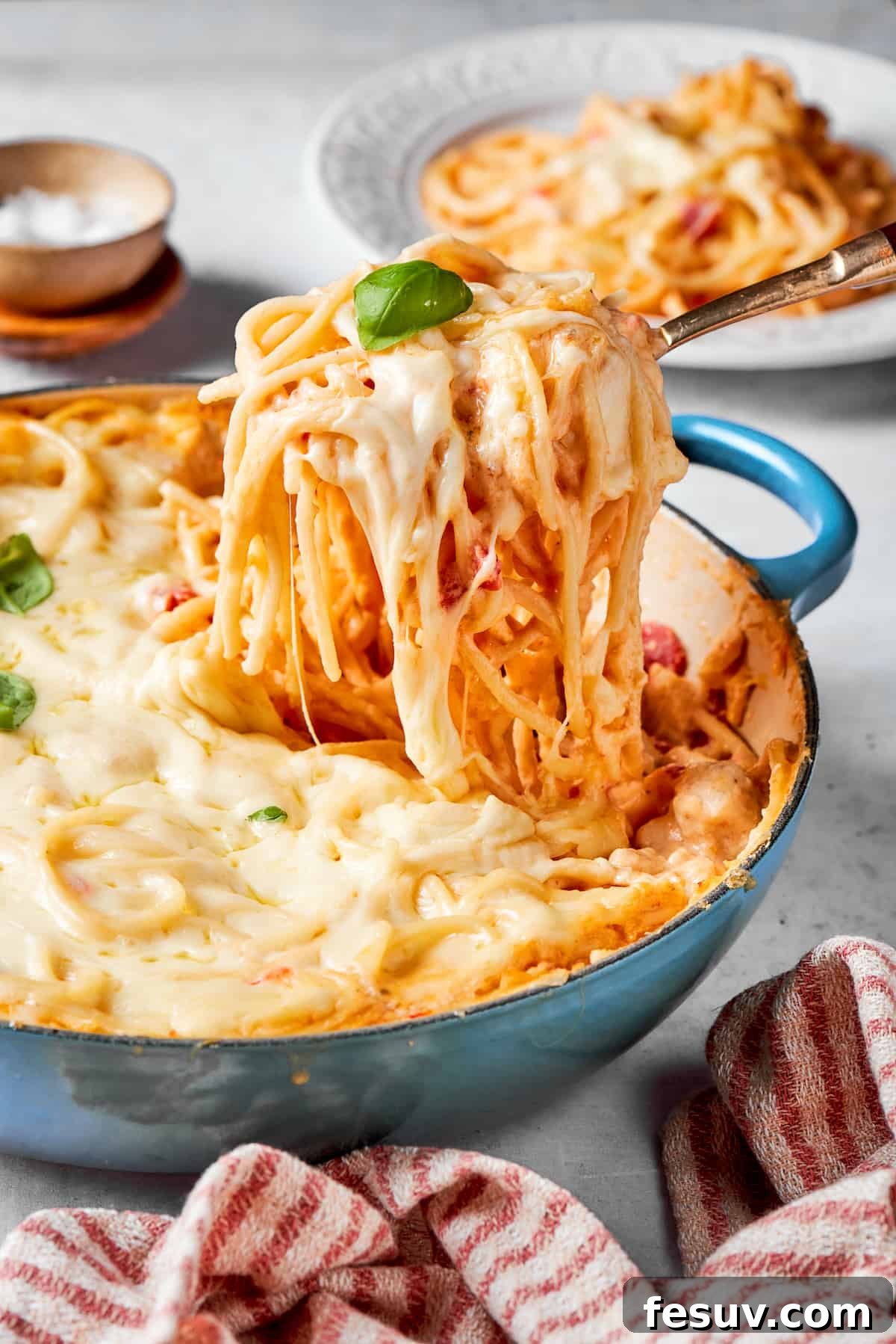 A serving utensil lifts out a potion of cheesy chicken spaghetti, showcasing the creamy sauce, tender chicken, and melted cheese.