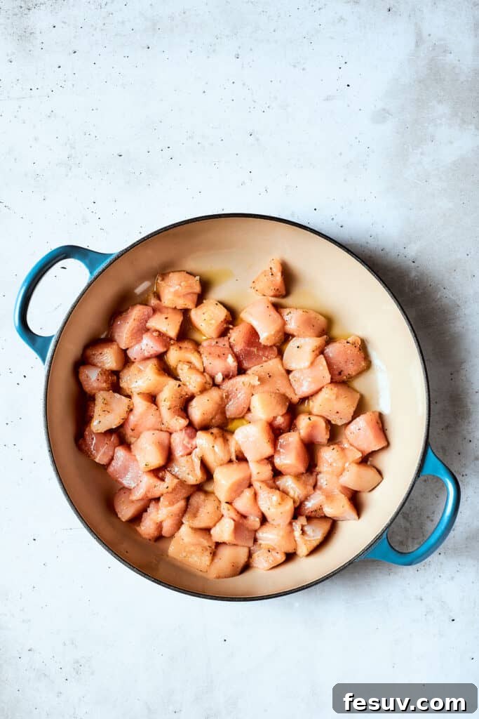 Pieces of seasoned chicken cook in a pot until golden brown.