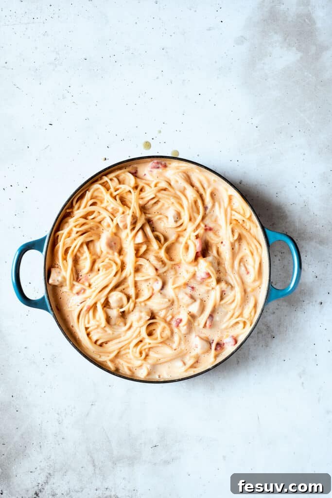 The chicken and spaghetti are thoroughly incorporated into the creamy sauce, ensuring every strand is coated.