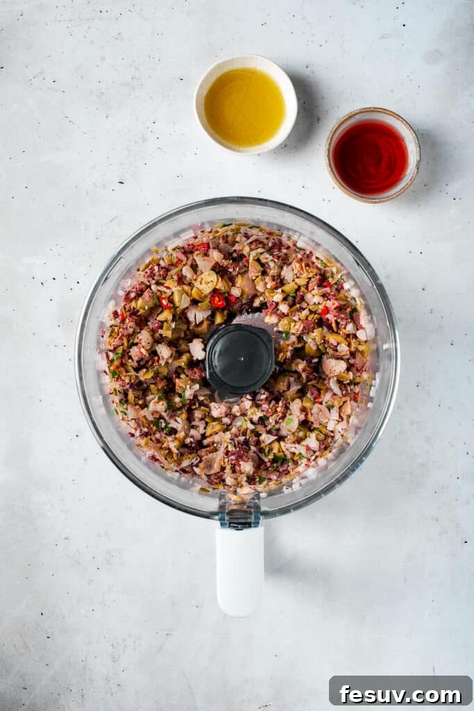 Finely blended olive salad mixture in a food processor, showing a coarse, textured consistency.