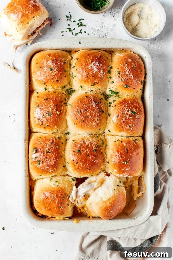 A tray of freshly baked, irresistible chicken bacon ranch sliders. A baking pan filled with golden-brown chicken bacon ranch sliders, beautifully melted and glistening, ready to be served, resting invitingly on a rustic wooden table.
