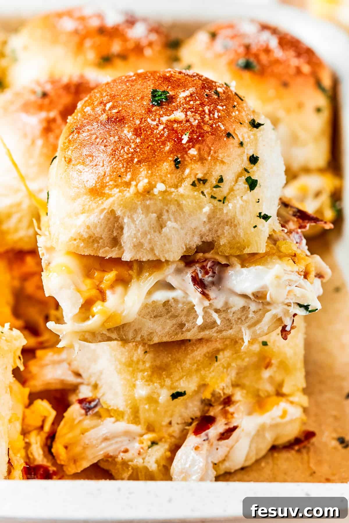 Stacked high: layers of savory chicken, crisp bacon, and melted cheese in a slider. Two perfectly stacked Chicken Bacon Ranch Sliders, showcasing the beautiful layers of tender shredded chicken, crispy bacon, creamy ranch, and gooey melted cheese, all ready for immediate enjoyment.
