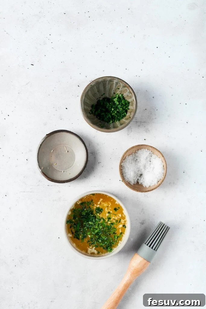 Individual components for the garlic-butter topping. Bowls showcasing melted unsalted butter, finely chopped fresh parsley, a pinch of fine-grain sea salt, and freshly minced garlic, all perfectly prepared for mixing into the savory butter topping.