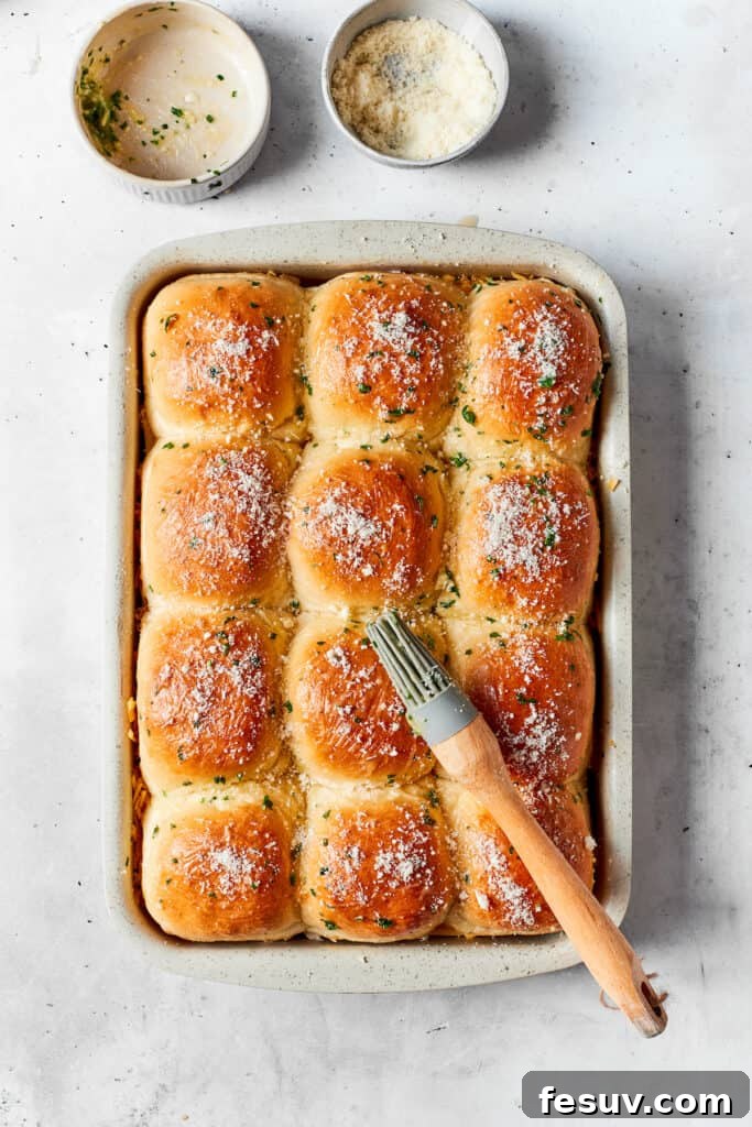 Brushing the slider tops with the remaining garlic butter. The tops of the Hawaiian rolls are gently and thoroughly brushed with the remaining melted garlic butter mixture, ensuring a lustrous, golden, and flavorful crust once baked to perfection.