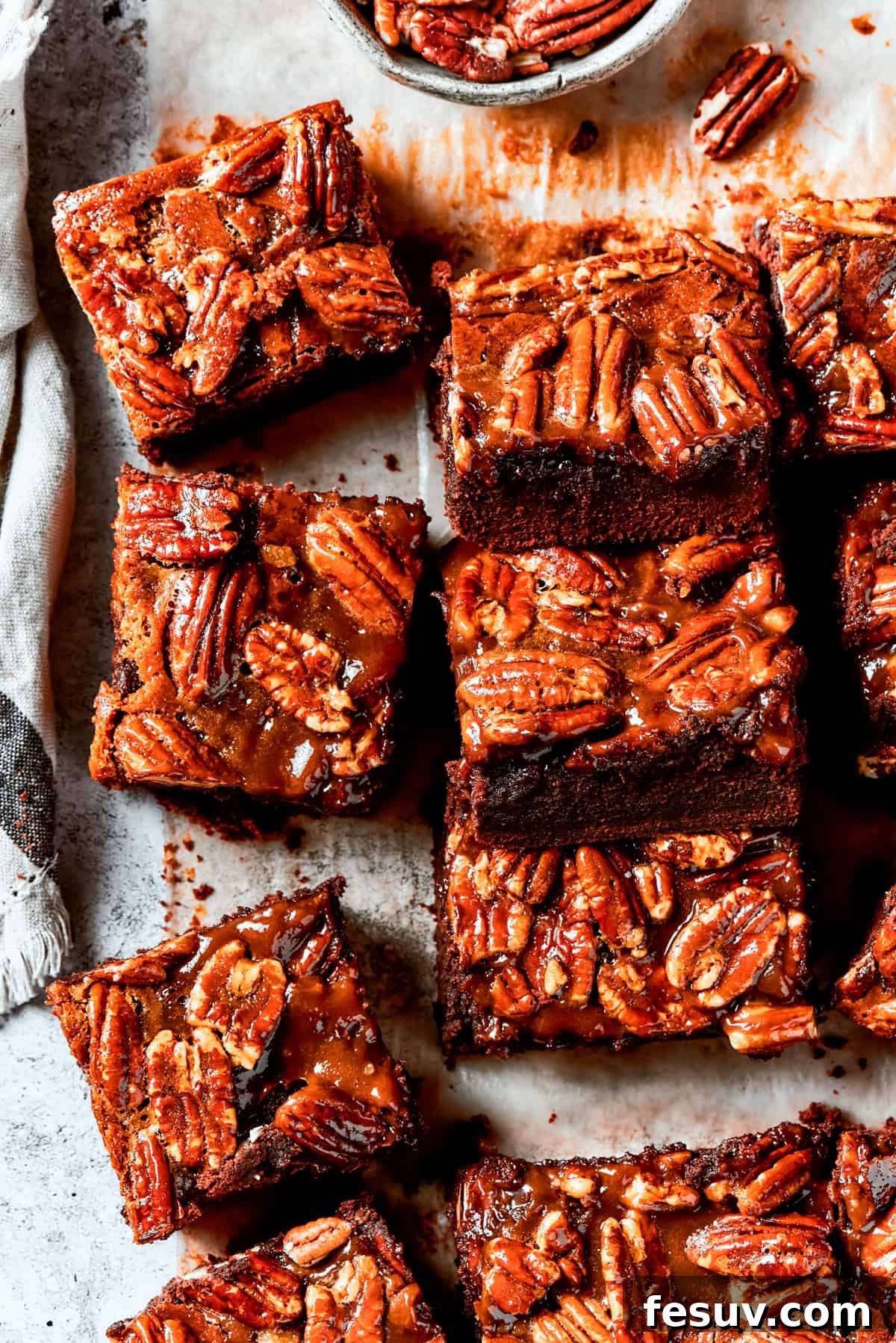 Pecan Pie Brownies: a perfect fusion of chocolate and nutty caramel goodness. Delicious Pecan Pie Brownies neatly arranged on parchment paper, showcasing their rich topping.