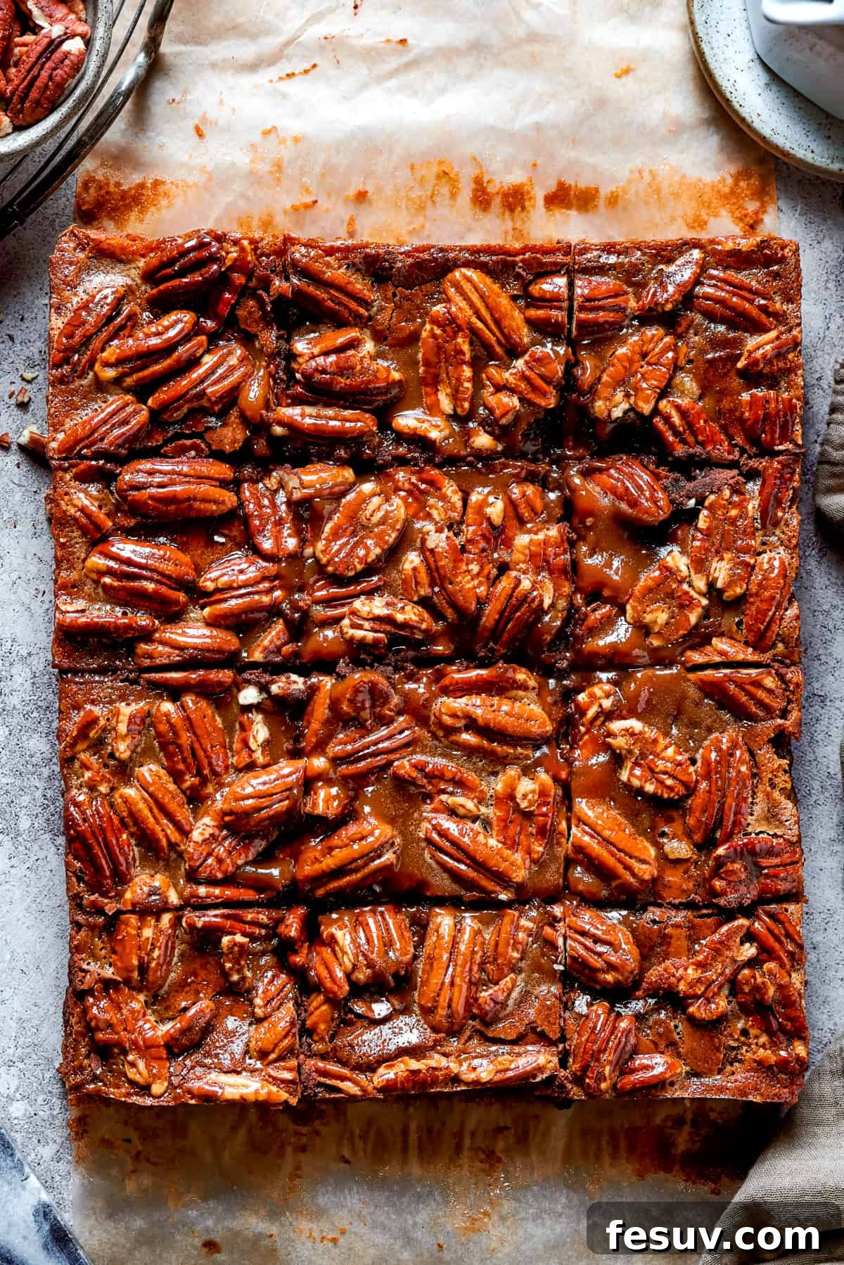 Beautifully cut pecan pie brownie squares, ready to be enjoyed. An overhead shot of a pan of pecan-topped brownies, freshly cut into symmetrical squares.