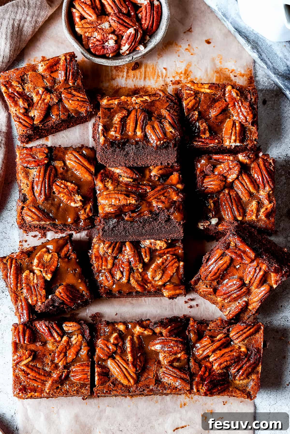 A tempting display of Pecan Pie Brownies, ready to be enjoyed. Several pecan brownie squares artfully arranged on a light, inviting surface.