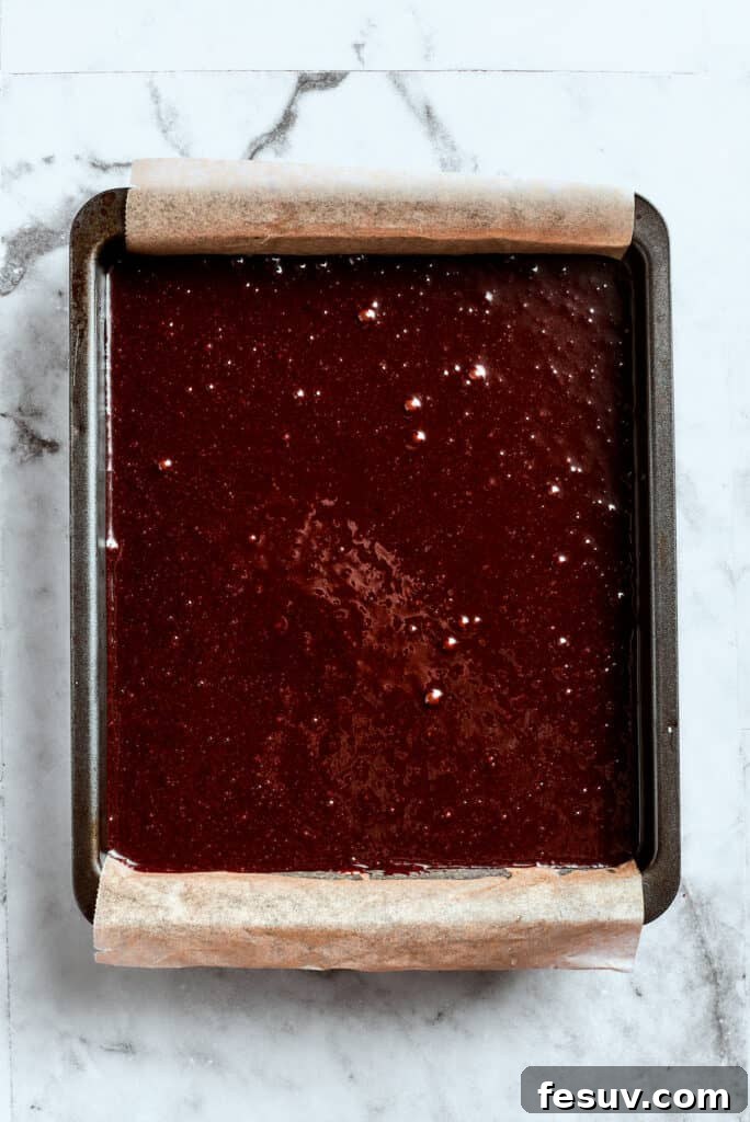 Spreading the brownie batter for a uniform bake. Rich brownie batter being evenly spread into a prepared baking pan.