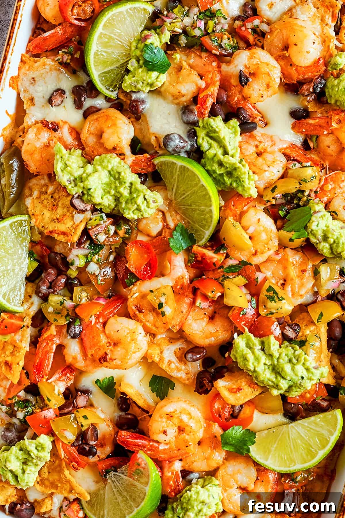 These crispy-crunchy Shrimp Nachos are piled with layers of flavor from creamy guacamole, juicy shrimp, and spicy, fresh pico de Gallo. Tortilla chips topped with shrimp, cheese, black beans, tomatoes, and a garnish of guacamole and slices of lime.